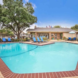 view of the pool at rosemeade with mature landscaping and brighly colored pool furniture