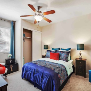 bedroom of model home with ceiling fan and two sliding closets
